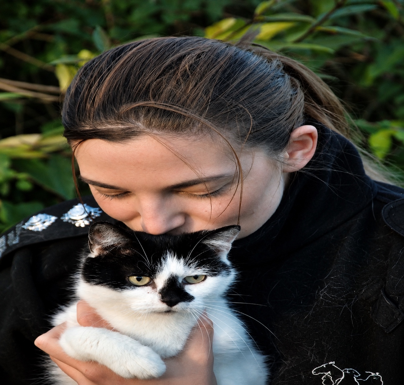 A person holding a black and white cat